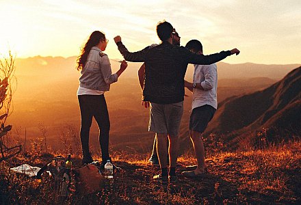 Eine Gruppe von jungen Menschen tanzt im Sonnenuntergang.