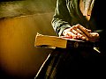 Eine Person sitzt auf einem Sessel und hat ein Buch auf dem Schoß liegen.