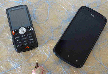 Auf einem Tisch liegt ein altmodisches Handy neben einem modernen Smartphone.