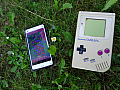 Ein Gameboy und ein Smartphone liegen nebeneinander im Gras.