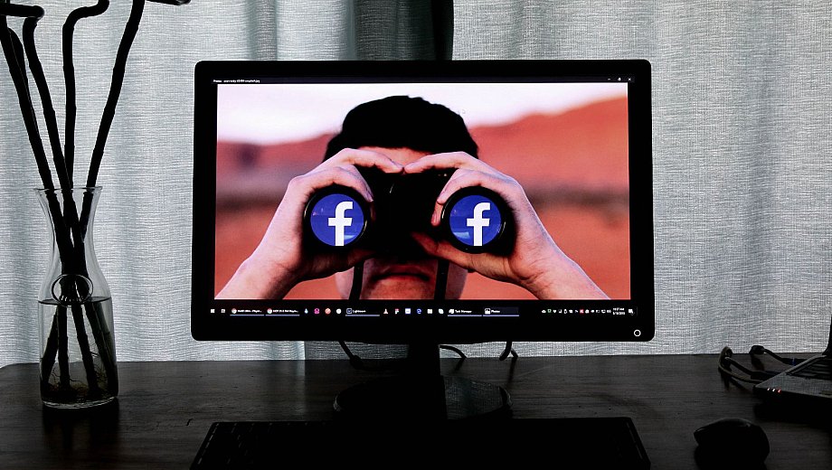 Person guckt durch Fernglas mit Facebook Logos