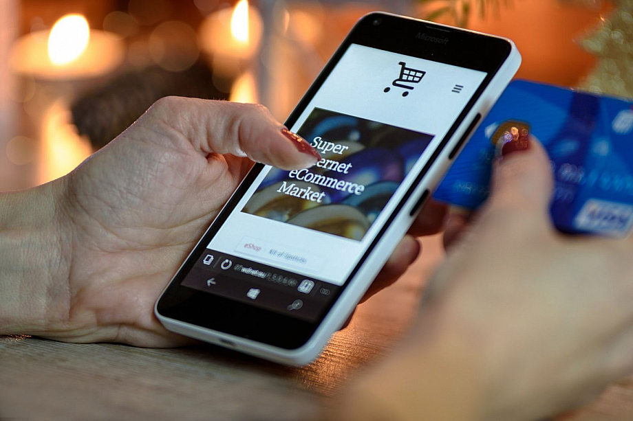 Online-Shop auf Handydisplay, daneben eine Kreditkarte