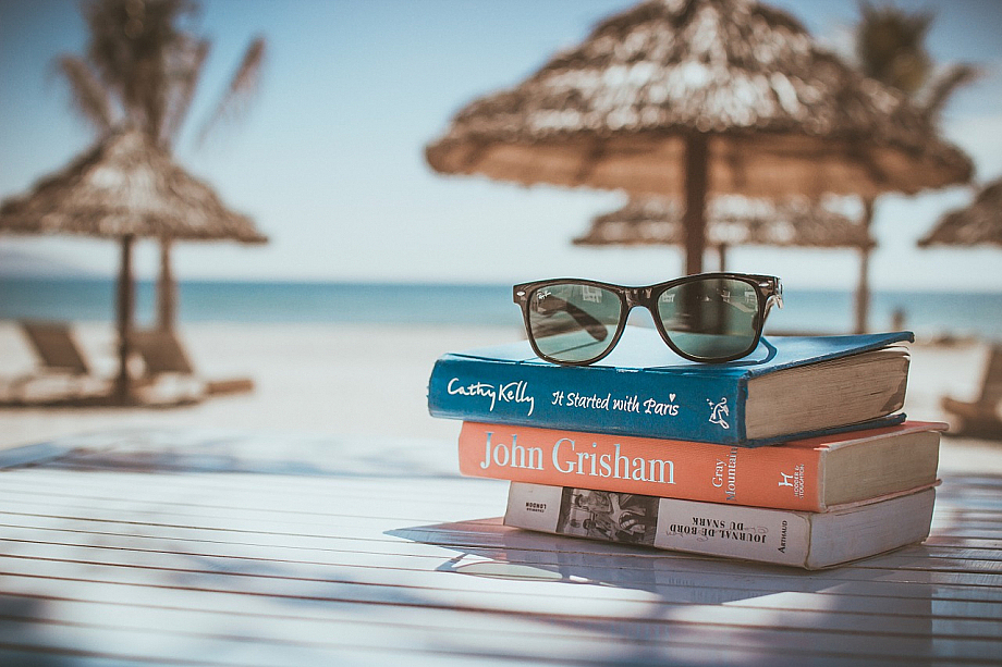 Stapel Bücher und eine Sonnenbrille am Strand