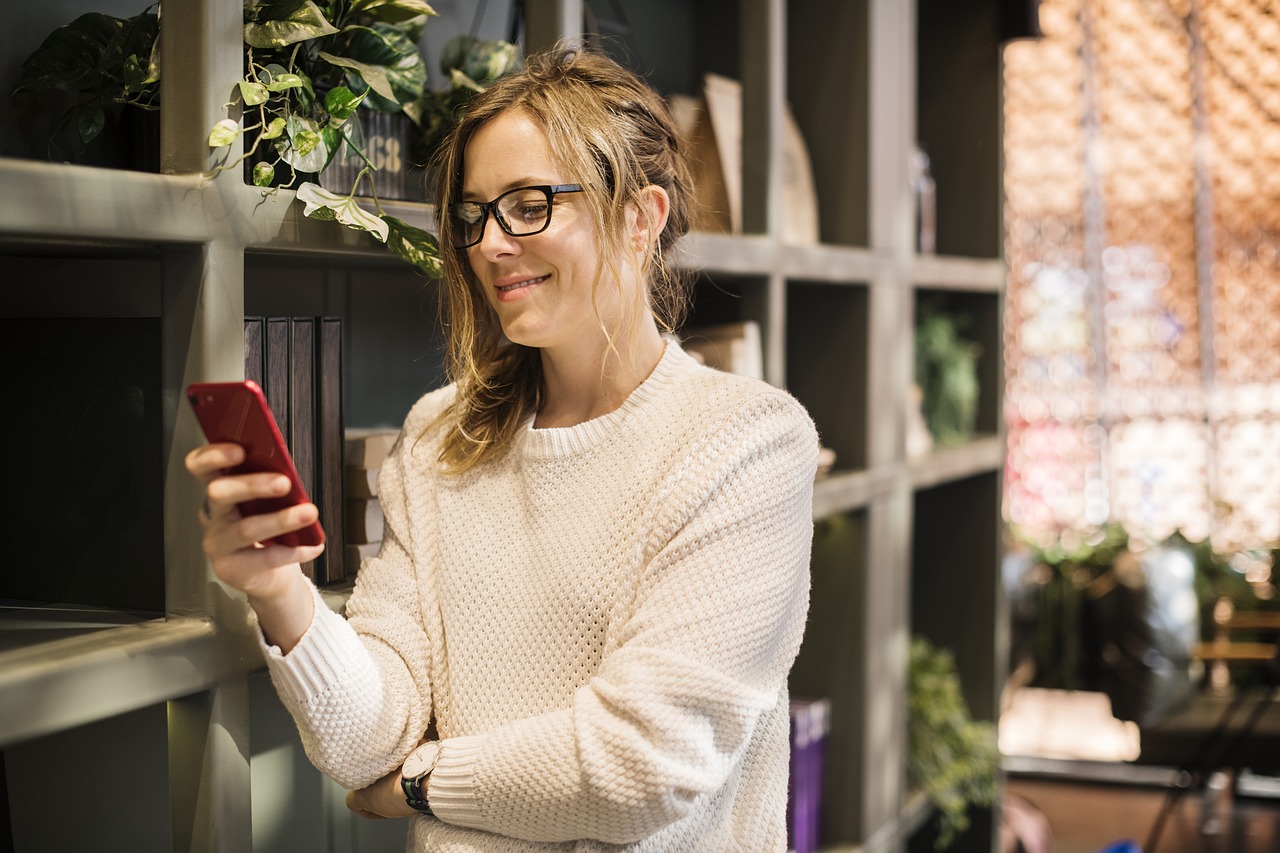Frau lehnt an einer Wand und liest auf ihrem Smartphone.