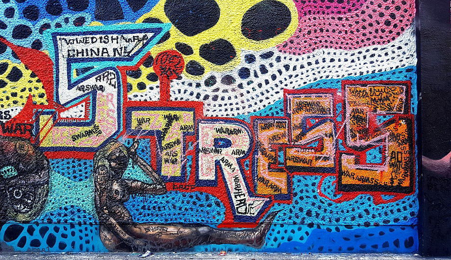 Graffitti an einer Wand, unter anderem das Wort Stress in bunten Großbuchstaben