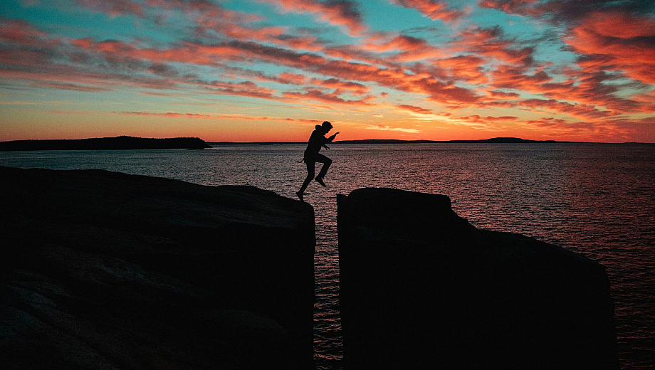Person springt im Abendlicht über eine tiefe Schlucht