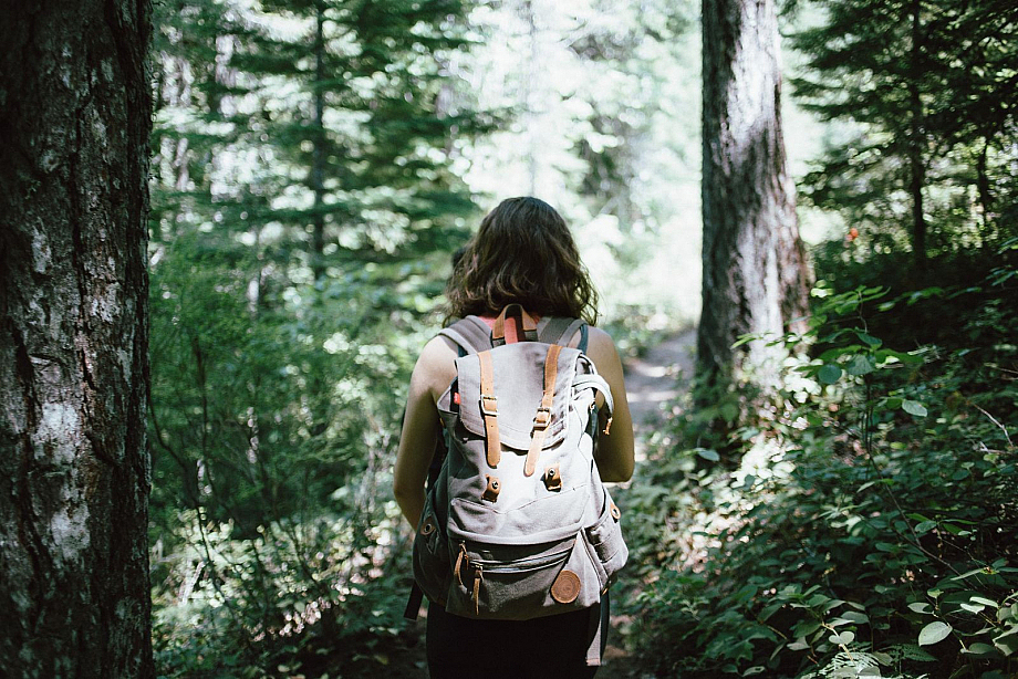 Frau mit Rucksack wandert durch den Wald