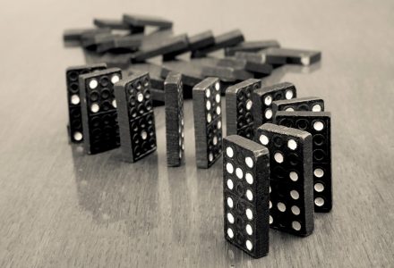 Dominosteine in einer Reihe aufgestellt, ein paar sind schon umgefallen, ein paar stehen noch.
