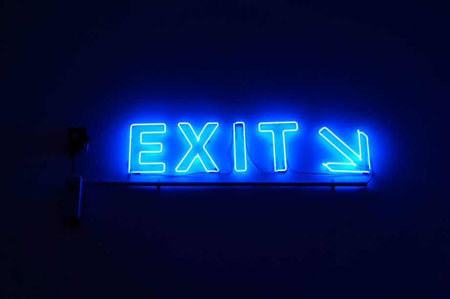 Blau leuchtende Buchstaben ergeben das Wort Exit. Hinter dem Wort zeigt ein Pfeil nach rechts unten.
