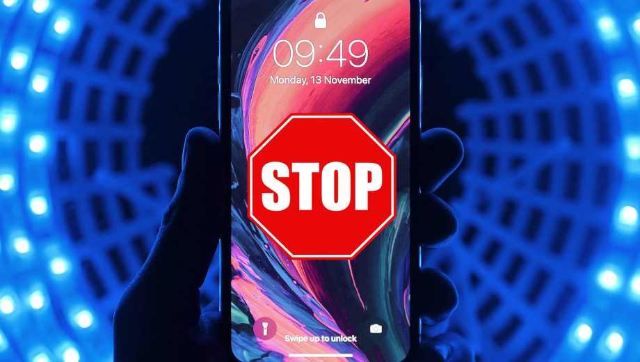 Blau leuchtender Hintergrund. Im Vordergrund hält eine Hand ein Smartphone mit leuchtendem Bildschirm hoch. Auf dem Bildschirm ist ein Stop-Schild zu sehen.