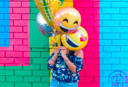 Frau mit bunten Emoji-Luftballons