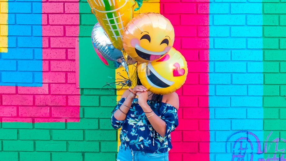 Frau mit bunten Emoji-Luftballons