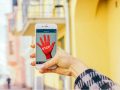 Rote Hand und das Wort Stop auf einem Smartphone-Bildschirm