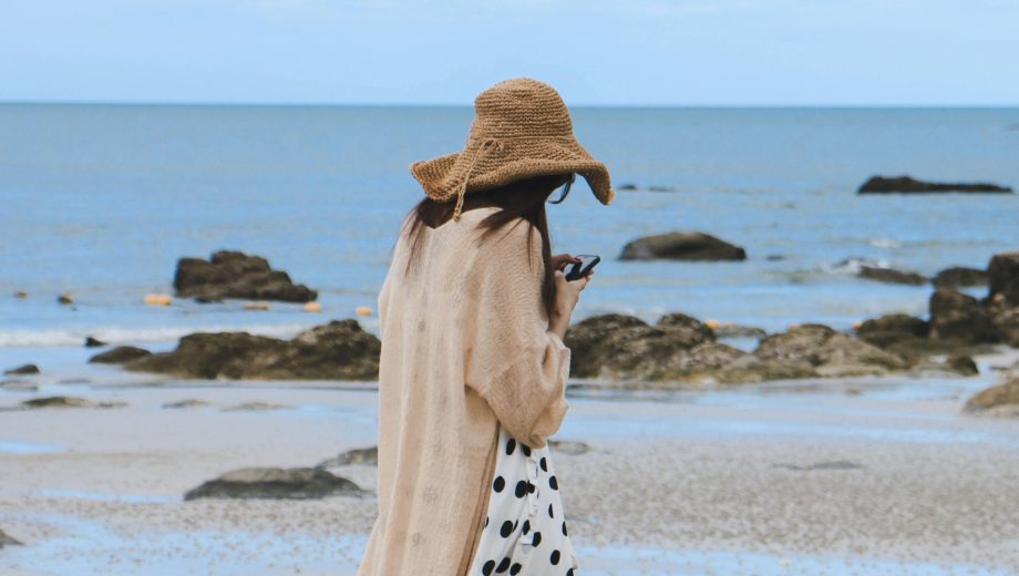 Frau am Strand guckt nur auf ihr Handy