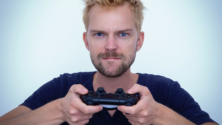 Mann hält Playstation-Controller und guckt angestrengt