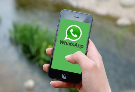 Handy in der Hand, Bildschirm zeigt WhatsApp-Logo