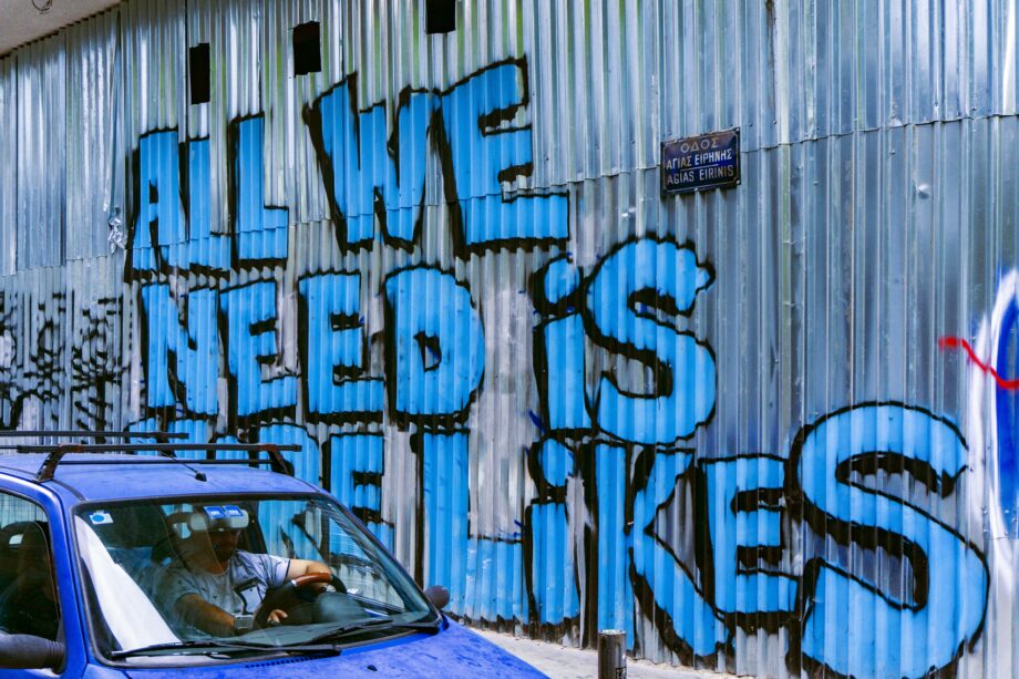 Graffito an einer Wellblechwand: All we need is Likes.