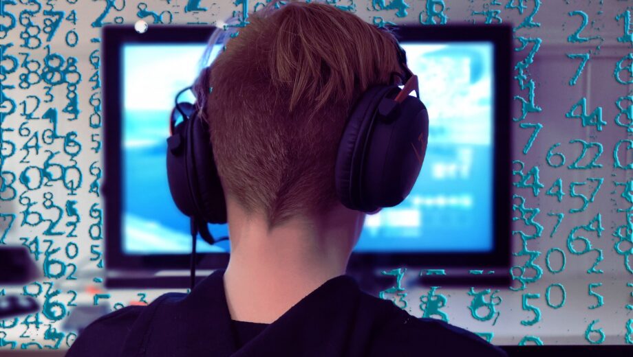 Junge vor Computer, um ihn herum fliegen Nullen und Einsen.