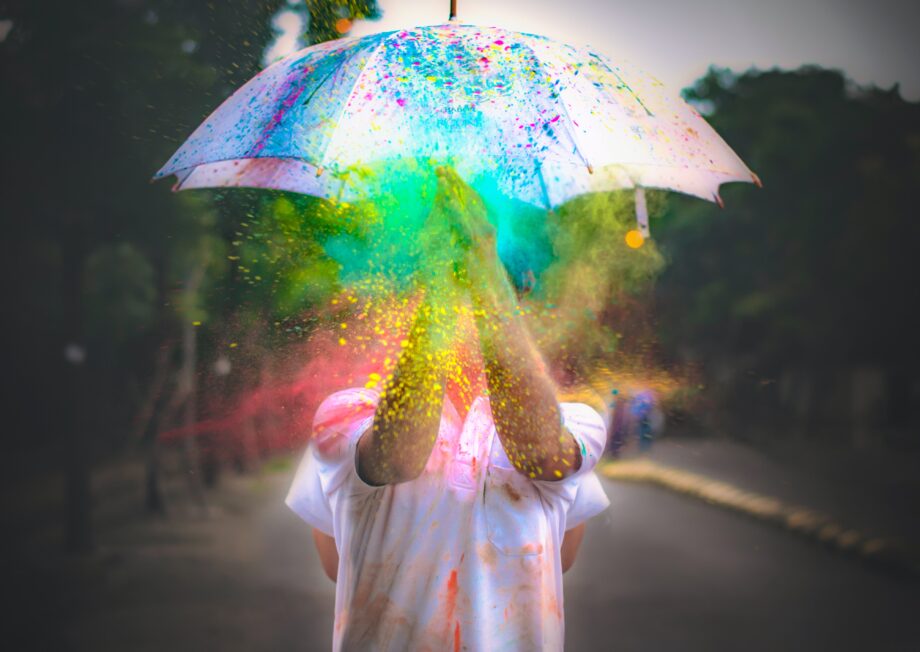 Weißer Regenschirm wird mit bunter farbe beworfen